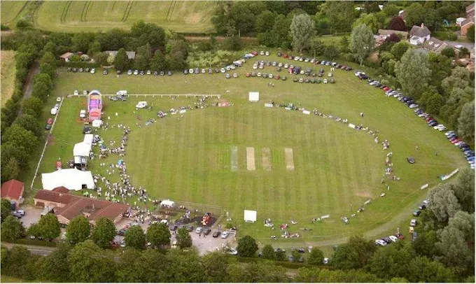 Aerial view of a fun day on the field, with stalls and marquees around the cricket square